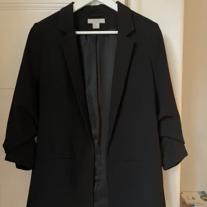 Svart kavaj - Svart kavaj från H&M med upprynkade ärmar. Sparsamt använd.