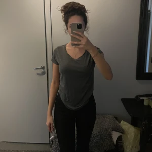 Grå T-shirt  - En basic grå T-shirt i tunt och luftigt material. Normal i storlek. Använt endast ett fåtal gånger och är i mycket bra skick!  Den är längre baktill (längd: 71cm) än den är framtill (längd: 62cm).  Axelbredd: 39 cm