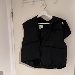 Väst  - Svart croppad väst med luva och dragkedja från NA-KD I utmärkt skick då jag använt den 1 gång tidigare 