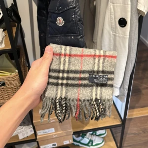 Burberry Halsduk - Burberry halsduk i utmärkt skick, inga hål eller missfärgningar, skick 9/10. 100% lammull i den korta modellen (110 x 15cm ca). Nypris 4600, mitt pris 1000kr men tar emot rimliga bud! Bara att skriva vid frågor eller funderingar, över 50 refs finns! :)