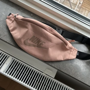 Axelremsväska  - Axelremsväska/midjeväska med fack på baksidan samt inuti. Hel och ren inga skador