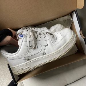 Nike Air Force 1 07 LX - Knappt använda Nike Air Force 1 LX i vitt med små metalliska nikeloggor. Slutsålda på Nikes hemsidanoch nypris ca 1900 på Farfetch. Skickas i sin originalförpackning. 