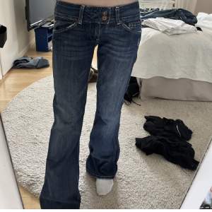 Lågmidjade bootcut jeans med coola knappar från pepe!Hade i två storlekar så det är det exakta paret på sista bilden men det är samma modell och färg (även om färgen ser gråare ut på sista)❤️ mått: midja- 40cm tvärs över, innerbenet- 77cm, ytterbenet- 96cm