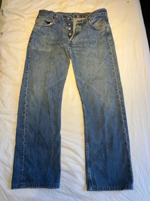 Levi's 501 med knappgylf (32x32) - Ett par av mina gamla levi's som jag har vuxit ur. Jeansen har inte använts särkskilt mycket. Byxorna har knappgylf, de är Regular fit (32x32). Priset går att diskutera