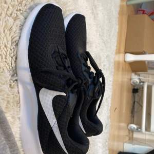 Ett par Nike skor som har blivit för små, svart och vita. Grön sula!