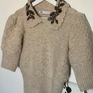 Stickad tröja - Stickad tröja med broderade blommor vid kragen🤍använd en gång. Ny pris: 500kr