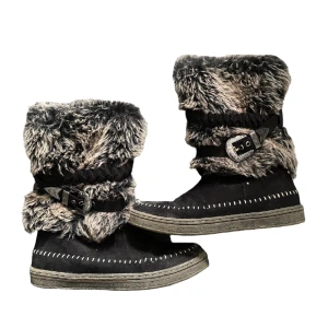 Fluffiga varma vinterskor - Häftiga svarta och grå/lila fluffiga vinterboots. Fin detalj med spännen på båda skorna. Öppnas med dragkedja. Finns en liten slitning vid ena spännet, och de är i använt skick. Storlek 37, men passar mig som ofta har 37,5 eller 38. 