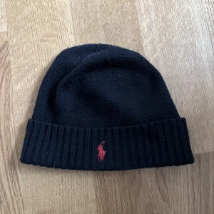Ralph lauren mössa - Hej! Säljer en Ralph lauren mössa, svart med röd symbol. Nypris - runt 500-600kr Mitt pris - 250
