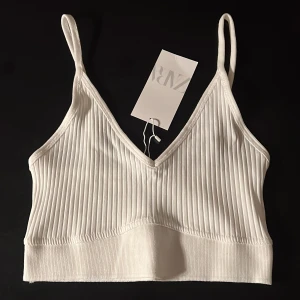 Helt oanvänd topp Zara! - Helt ny topp från Zara, helt oanvänd och utan defekter! Vit och lite ribbad. Jättefin, men passade inte mig. Lappen är kvar - storlek M 