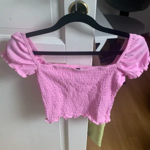 Ljusrosa topp med puffärmar - Fin ljusrosa topp med smock och puffärmar som är oanvänd. Är i ett stretchiga material.  