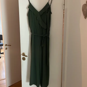 Grön byxdress - Grön lite v-ringad byxdress med knyte fram. Gott skick, använd 1 gång. 