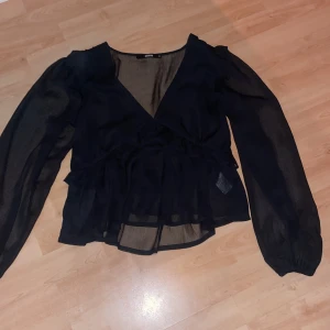 Svart blus långärmad volang tröja - Svart blus långärmad troja med volanger, vringad och resor vid ärmed