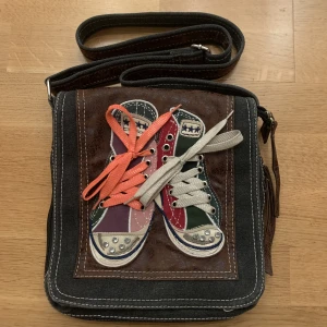 Väska med Converse  - En axelremsväska som är köpt utomlands med conversetryck på. Väskan går att justera till önskad längd och är fortfarande i gott skick :)