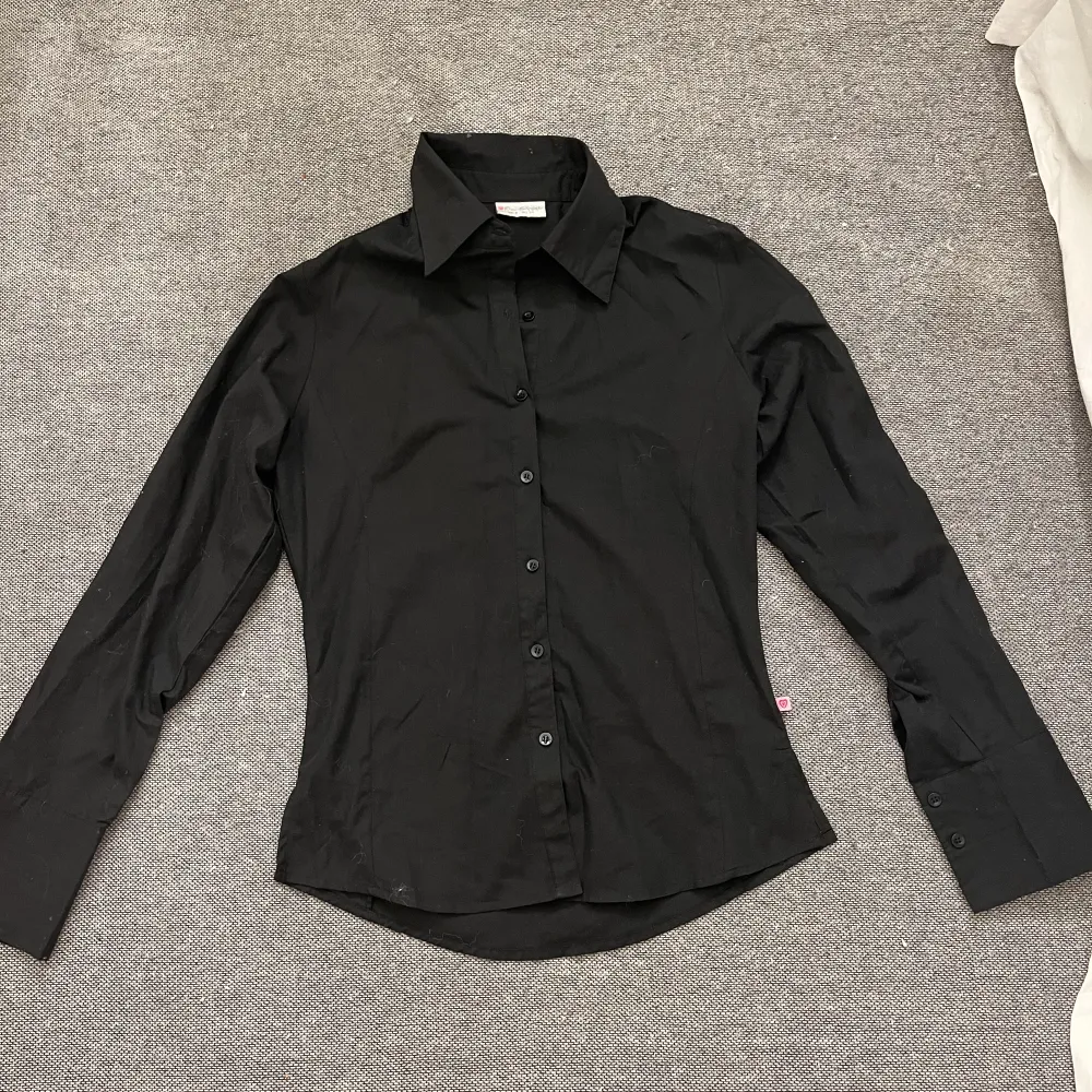 En svart skjorta i nyskick . Skjortor.