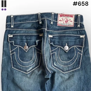 True religion jeans #658 - True Religion jeans i model Nathan Giant Big T 💜 Tag 34W 💜Midja (rakt över) 41cm 💜 Innerben 83cm 💜 Ytterben 117cm 💜 Benöppning 22cm 💜 Rips på knäna och fläckar på framsidan. Insydda i midjan 💜Våra mått blir W=32 och L=32 💜 Men jämför alltid måtten💜