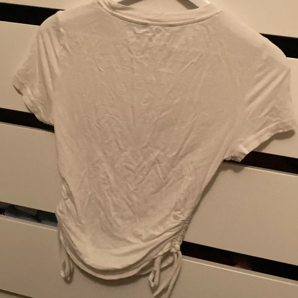 Gullig basic T-shirt med snören på sidan för att justera längd, inget tecken på användning. T-shirts.