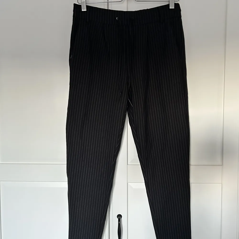 Svarta kostymbyxor med vita ränder från Only. Stretchigt material. . Jeans & Byxor.
