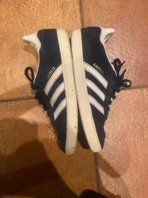 Adidas Gazzelle skor - Så fina mörkblå skor, Adidas Gazelle💙💙Skorna är i superbra skick inga hål eller slitningar💗💗 Skorna är i storlek 38 o är så snygga både till jeans men också kjol o klänning i sommar✨✨