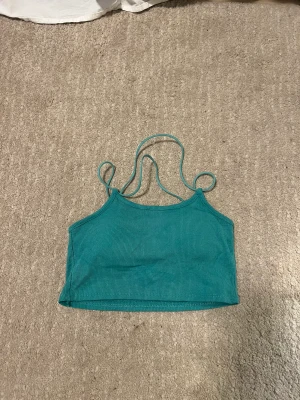 Magtröja med korsning i ryggen - Jättefin magtröja med snörning i ryggen som bildar ett kors, kan visa tydligare om man skriver. Färgen är väldigt stark och man ser väldigt Tanned ut i den. Den är turkos och älskar den verkligen. 