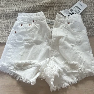 Vita jeansshorts - Vita jeansshorts med slitningar och hög midja. Aldrig använda med lapp kvar!