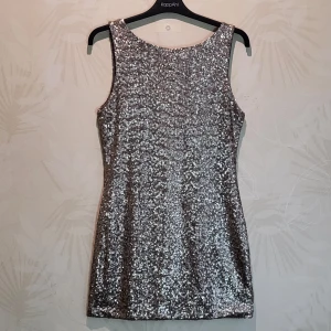 Klänning - Paljettklänning i silver. Ny/oanvänd. Öppen i rygg.