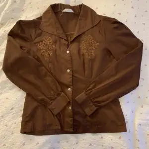 En vintage brun skjorta med fina broderier på framsidan ( bild två ). Märket är oklart men se bild tre för material och tvätt beskrivning. 