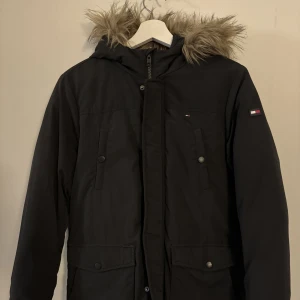Vinterparkas Tommy Hilfiger - Junior - Säljes en svart parkas från Tommy Hilfiger. Den är i juniorstorlek 152. I mycket fint skick.