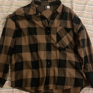 Flanellskjorta - Brun och svart flannel skjorta. Helt oanvänd, fick den som present men det är inte riktigt min stil.