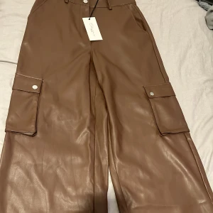 Bruna skinn cargos  - Bruna skinn cargos byxor som är jätte fin och aldrig använda. Längden sitter bra på mig som är 156. Säljer pågrund av att det inte är min stil. 