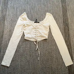 En vit kort långärmad tröja med superfint knyte fram. Helt oanvänd och prislapp kvar. Väldigt skönt material och stretchig.💕