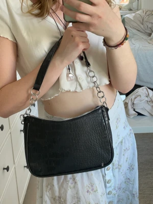 Svart liten väska i fejkläder   - Svart väska i fejkläder, väskan är i nyskick 