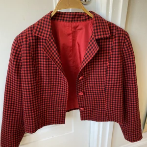Croppad kavaj  - Röd rutig croppad kavaj med vida axlar, perfekt skick som ger rock n roll och 70-90 tals känsla, perfekt för vår och sommar. 
