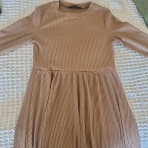 Klänning. - Fin beige/brun klänning med långa ärmar och utsvängt nedtill.  Som oanvönd 