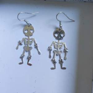 Silverörhängen i form av två förälskade skelett.