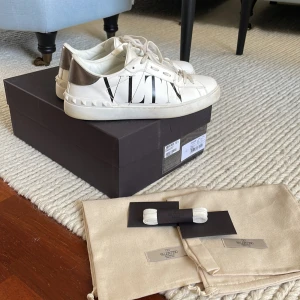 Valentino skor  - Säljer nu mina vita valentino skor med VLTN tryck. Skorna är i bra skick ca 8,5/10 och allt OG medkommer (äkthetsbevis, extra skosnören, box och dustbags). Storlek 41, men passar även mig som vanligtvis har storlek 42.