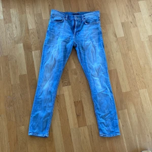 Jeans från Nudie - Ett par jeans från Nudie i slim fit och lite stretch i tyget. Storleken är 32/32 ovh har en lätt tvätt i designen. 