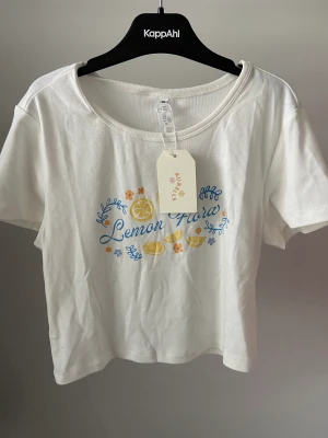 Baby tee med tryck - Baby t-shirt med blom tryck och text. Är oanvänd då den var en gratis gåva i en annan beställning. 