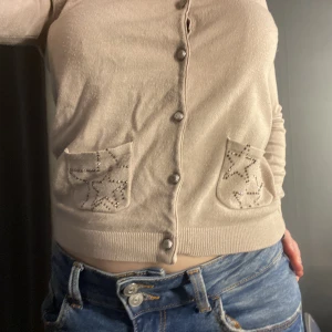 Kofta  - Beige kofta med knappar och stjärnor på vänster arm och på båda fickor. Tunn och ganska kort på mig.☺️