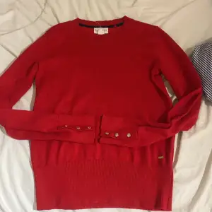 En röd långärmad tröja från Lindex,Holly white, guldiga knappar på armarna, säljs p.g.a ingen användning,nästan aldrig andvänd❤️köpt för ungefär 600kr köp pls🙏🏻🙏🏻