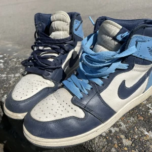 Jordan 1 high Obsidian - Skit snygga och köpta här på plick. Säljer igen då de inte riktigt passade. Dom är i ganska bra skick och bekväma. Orginal pris var enligt säljaren 1900kr.  Andra bilden är från säljaren. Kan tänka mig sänka priset lite. 