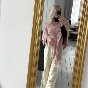 Poncho  - Stickad mjukisponcho med fransar i ett skimmrande gammelrosa material💗✨