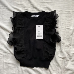 Topp - En svart topp med volanger på sidorna ”ruffle fetstil knuttes top” som har lappen kvar ℹ️Ordinarie pris: 349 kr ℹ️står xxs på lappen men passar även xs