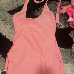 Rosa kläning  - Rosa kläning med knytning vid halsen. Köpt förra sommaren ej använt köpt för 200kr