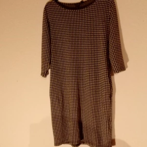 Hundtandsmönstrad klänning  - Tunika/klänning i mjukt tyg som har 3/4 ärm samt fickor 