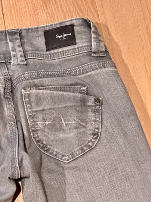 Lågmidjade Pepe jeans  - Jättefina lågmidjade ”Venus” raka jeans i färgen grå. Använda fåtal gånger. Säljer då de tyvärr inte kommer till användning längre. Strl: 25/34 Innebenslängd:83,5 cm midjemått (tvärs över):ca36 cm