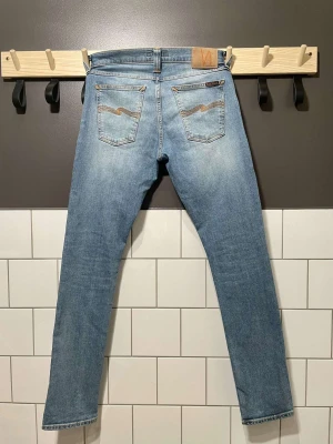 Nudie Jeans - Ett par snygga ljusblåa nudie jeans i mycket fint skick. Ny pris är cirka 1300-1600 kr, vårt pris 449 kr. Storleken är 30/32 och är perfekt i storlek. Tveka inte att höra av dig vid minsta fråga