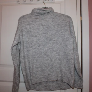 Turtleneck stickad tröja  - Grå stickad turtleneck tröja. Den har en liten fläck vid kragen, som dock inte syns alls på grund av turleneckan. Den har en fin passform. Kan levereras i Göteborg zon1 och 2 inom västtrafiks rese handlingar. Helst cash då jag inte har swish. Detta kan dock lösas. Lägg bud 