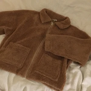Teddyjacka - Supermysig jacka/ kofta i teddymaterial. Den är beige och har en liten krage samt två fickor där fram. Tjockleken är som på en kofta så den är perfekt för vår och sommar. Märket är NLY trend. Använd ett fåtal gånger.