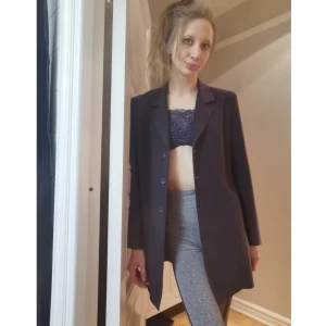 Number one by Kappahl lång kavaj strl. 38 - En lång, snygg kavaj med knappar framtill och slitsad längst ner på höger/vänster. Har inga fickor. Fungerar att styla upp med de flesta plaggen. Den är i fint skick och inga konstigheter!! Längden är på 83cm.