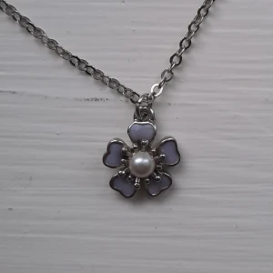 Halsband med lila blomma - Fint halsband som tyvärr inte kommer till användning. Frakt 11 kr. Se min profil för fler smycken.